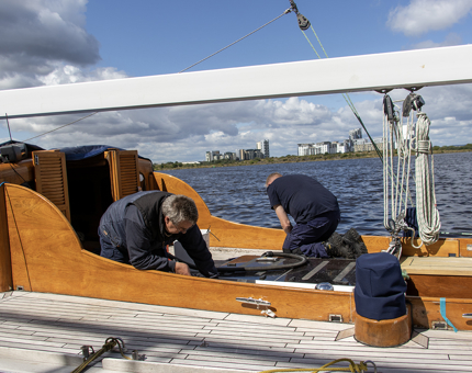 Two members of the Maintenance Team kneeling as they work on the racing yacht, Bloodhound.