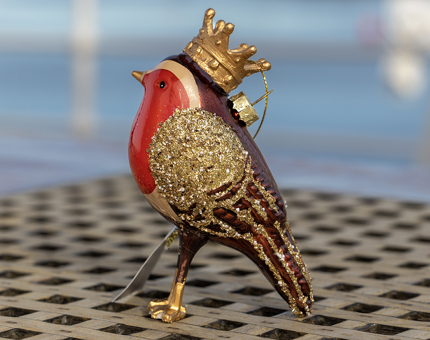 An ornamental robin Christmas decoration wearing a gold crown.