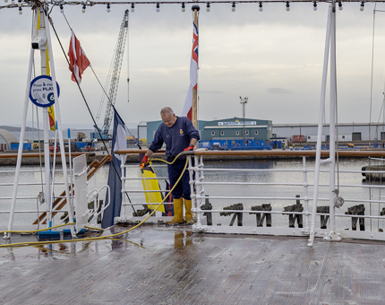 A member of Maintenance team hosing down the Verandah Deck.