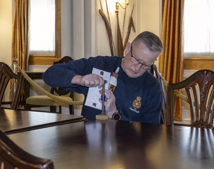 A man from Maintenance working on the State Dining Room wooden table.