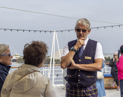 A male Visitor Assistant speaks to two women on the Verandah Deck.