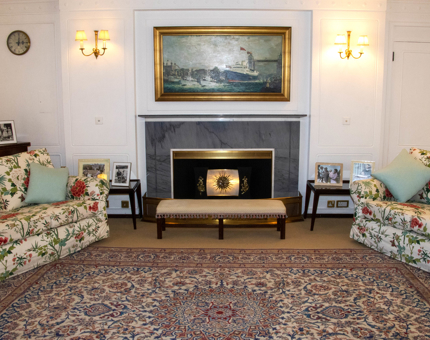 Britannia's State Drawing Room with a painting over the fireplace, two armchairs and a patterned rug on the floor.