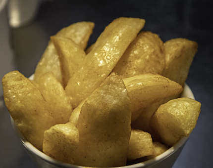 Close-up of a bowl of crisp potato wedges.