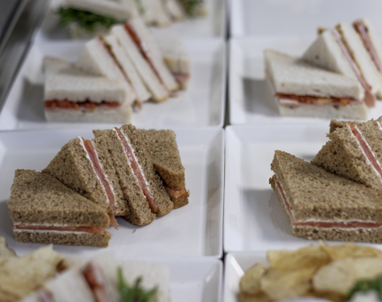 A selection of sandwiches on plates including smoked salmon and cream cheese and roasted ham and tomato.